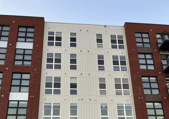 The outside of a commercial building with bricks and white siding