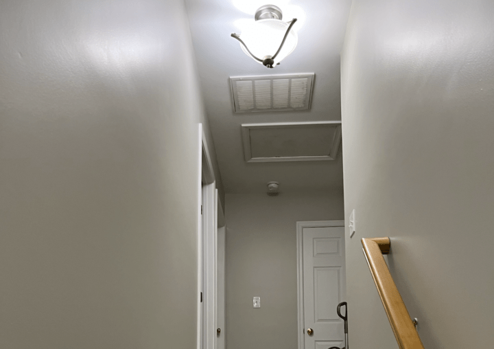 A bedroom with grey walls, white trim, and beige carpet