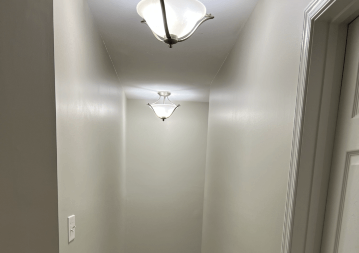 A bedroom with grey walls, white trim, and beige carpet