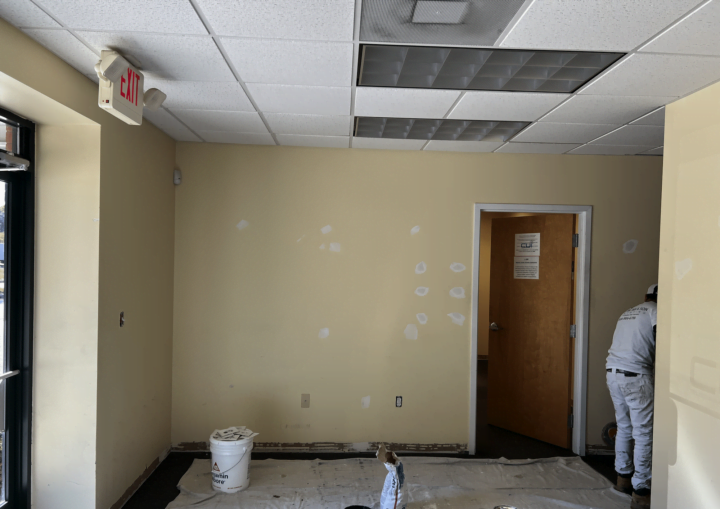 A yellow commercial office space with holes patched in the walls
