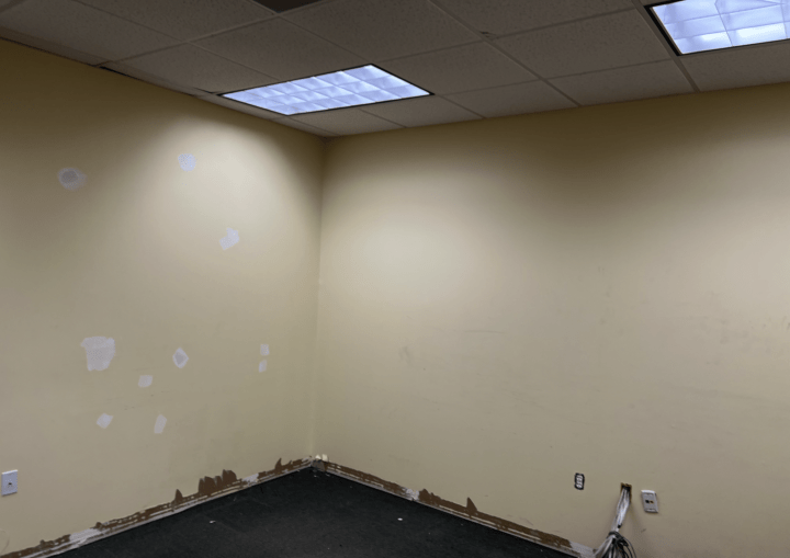 A yellow commercial office space with holes patched in the walls
