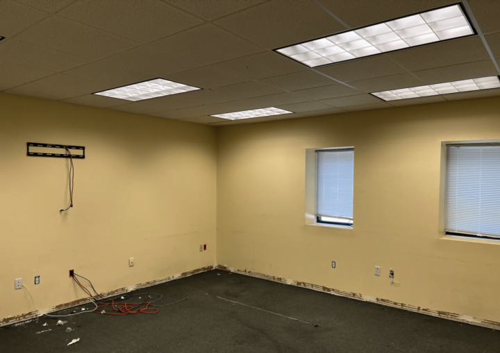 A room with peeling yellow walls and old carpet is in need of repainting