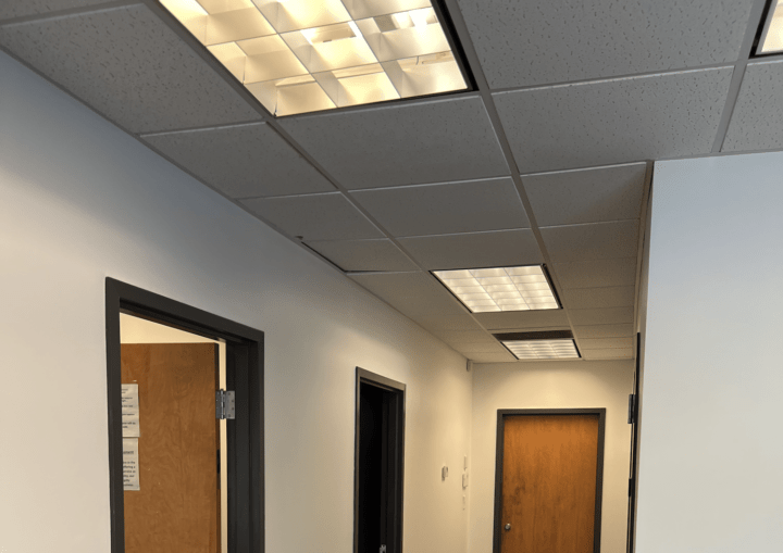 A hallways with brown doors, white walls, dark grey flooring and dark grey trim