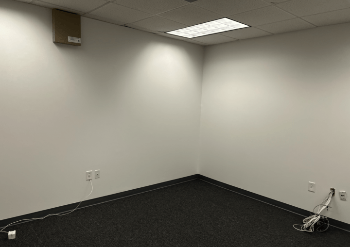 A commercial office space with white walls and dark grey carpeting