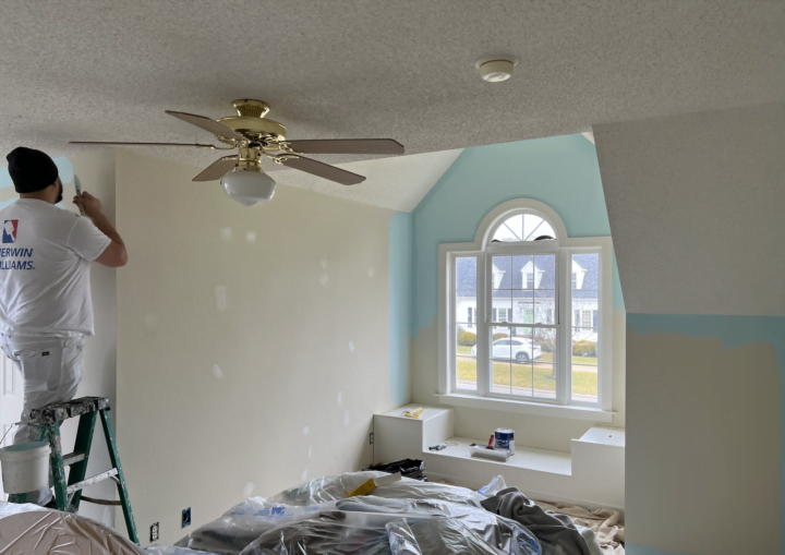 A man gets started painting a room light blue