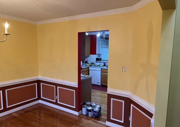 A dining room with red below the chair rail and yellow above
