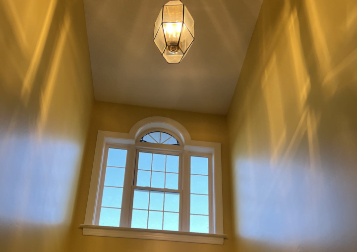 A foyer entrance with white walls and a pendant light