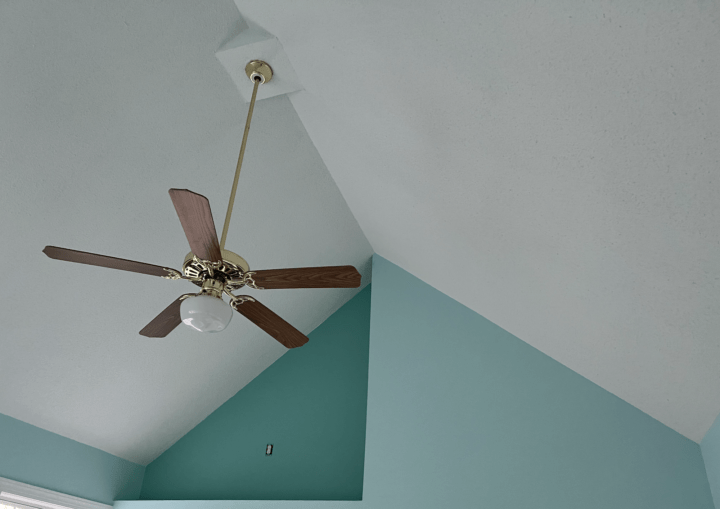 A room with a high ceiling and blue walls and a ceiling fan
