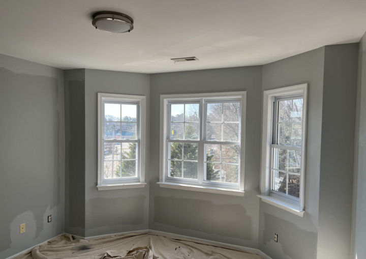 A room with a bay window being painted grey