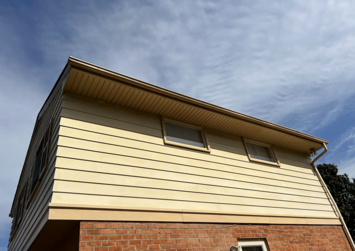 The outside of a house with siding and bricks against a blue sky