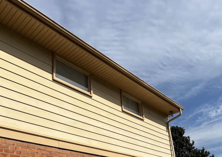 The outside of a house with siding and bricks against a blue sky