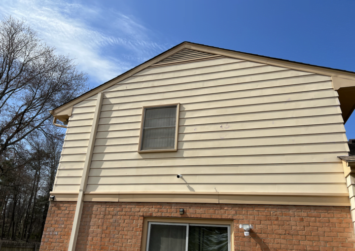 The outside of a house with siding and bricks against a blue sky