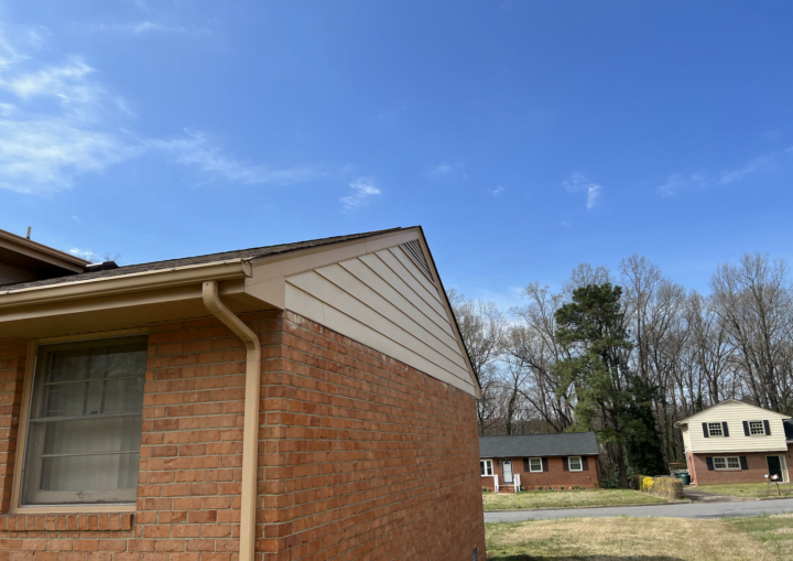 The outside of a house with siding and bricks against a blue sky