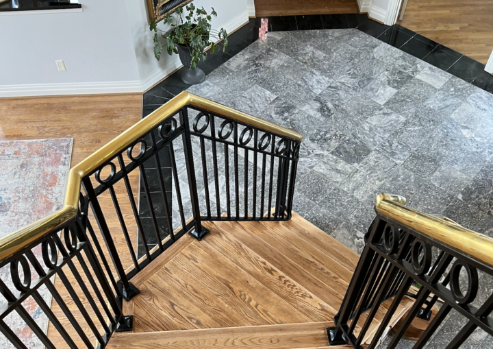 A wooden staircase leads down to a foyer with a stone floor