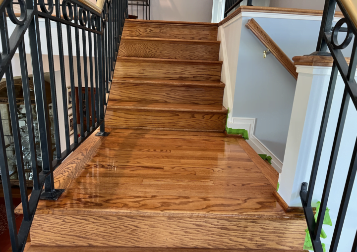 Green painters' tape lines the baseboards of the wall along a wooden staircase
