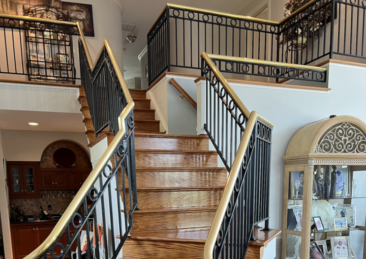 A foyer entrance with crisp white walls and a grand staircase with wooden stairs and a wrought iron handrail