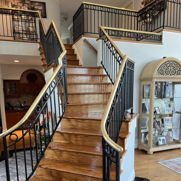 A foyer entrance with crisp white walls and a grand staircase with wooden stairs and a wrought iron handrail