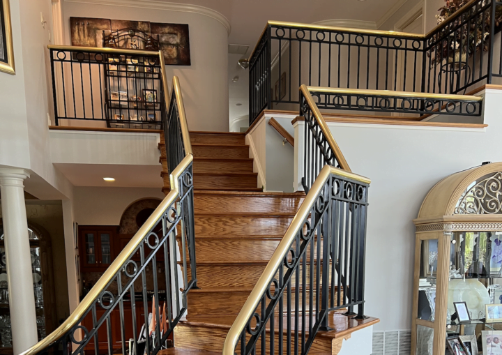 A foyer entrance with crisp white walls and a grand staircase with wooden stairs and a wrought iron handrail