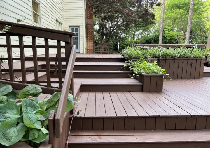 A freshly painted wooden deck, stairs, and bench in matching brown color