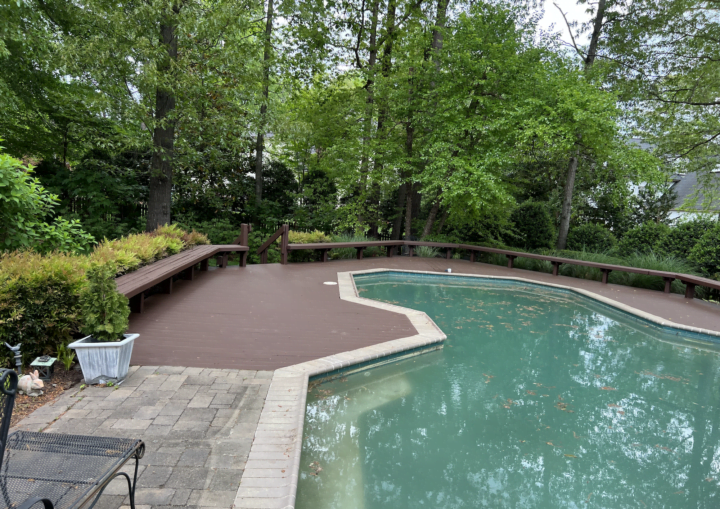 A pool sits in the middle of a freshly painted brown, wooden deck