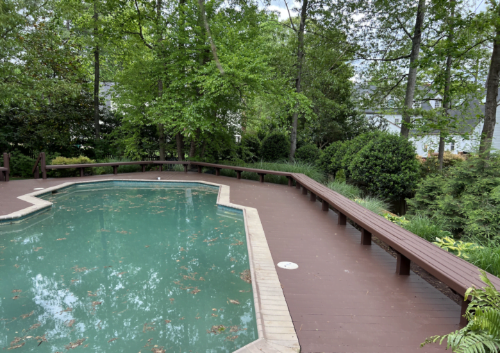 A pool sits in the middle of a freshly painted brown, wooden deck