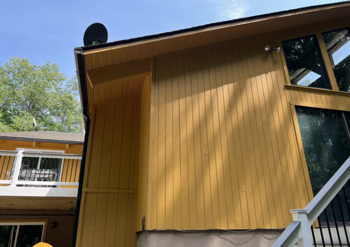 The outside of a freshly painted, modern house in a goldenrod color