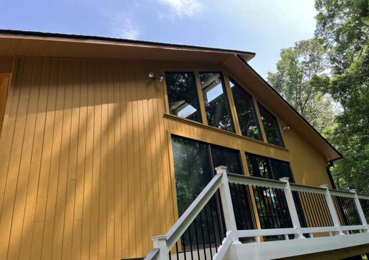 The outside of a freshly painted, modern house in a goldenrod color