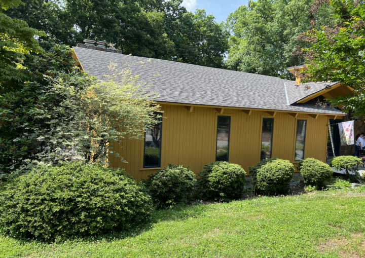 The outside of a freshly painted, modern house in a goldenrod color