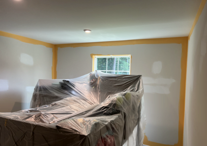A room is starting to be painted with yellow paint around the edges of walls