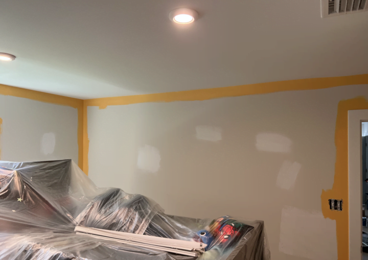 A room is starting to be painted with yellow paint around the edges of walls