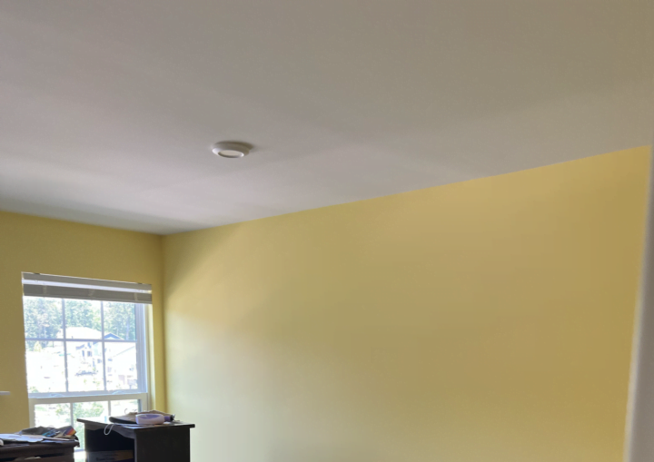 A room painted bright yellow with white baseboard