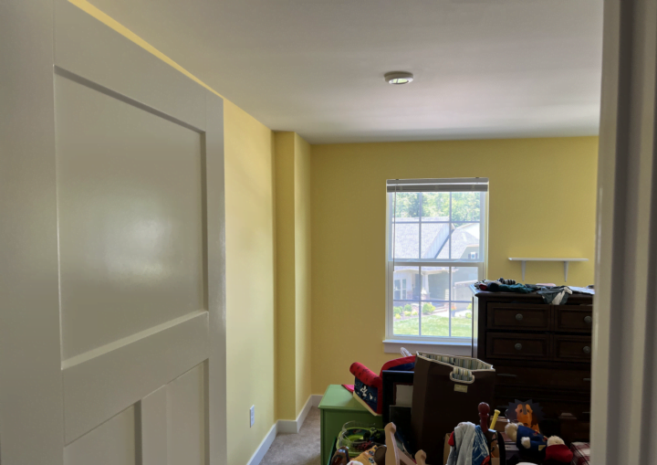 A room painted bright yellow with white baseboard