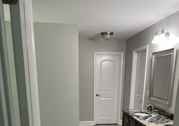 A bathroom with grey walls and grey tile flooring.