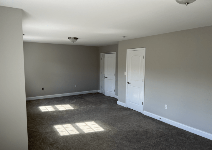 A room with grey walls and white doors and trim with grey carpet