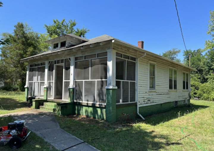 A house with chipped and peeling siding is prepped for painting