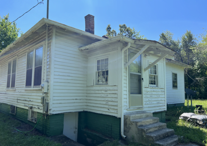 A house with chipped and peeling siding is prepped for painting