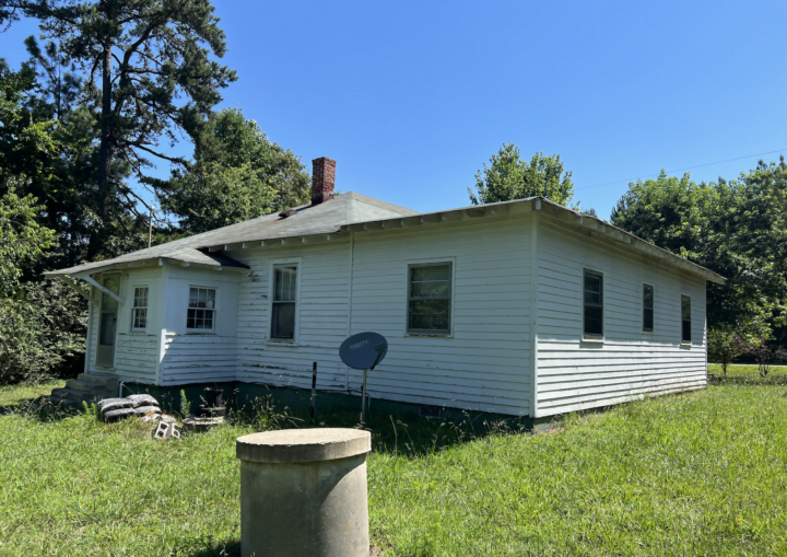 A house with chipped and peeling siding is prepped for painting