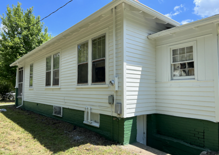 The back of a one story house with green basement trim