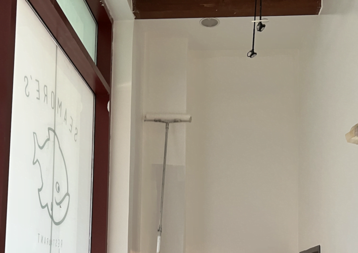 A man paints a tall wall with a roller