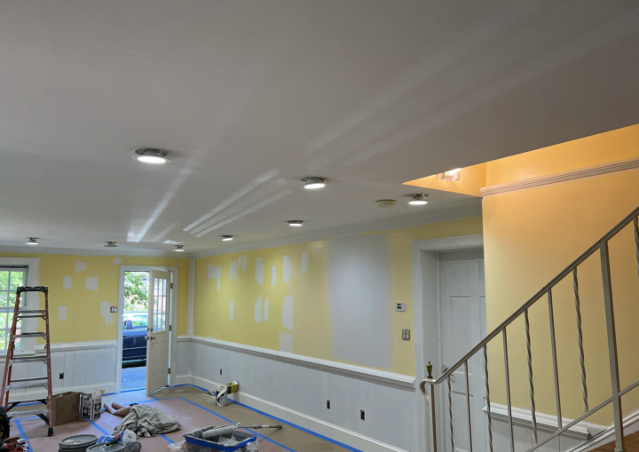 An in-progress photo of a room being painted sunshine yellow with white wainscoting and trim