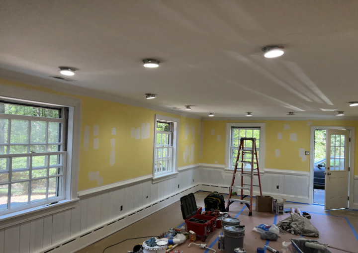 An in-progress photo of a room being painted sunshine yellow with white wainscoting and trim