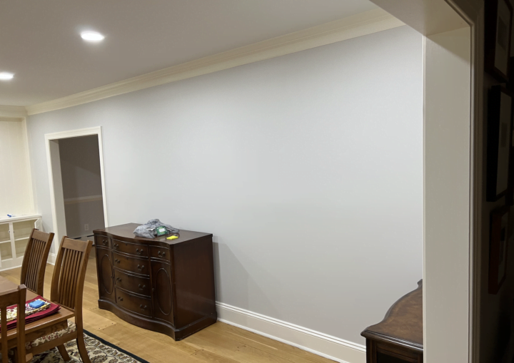 An off-white wall in a dining room with white trim